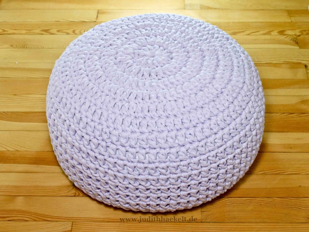 Rundes pastell-lila gehäkeltes Bodenkissen auf Holzfußboden
