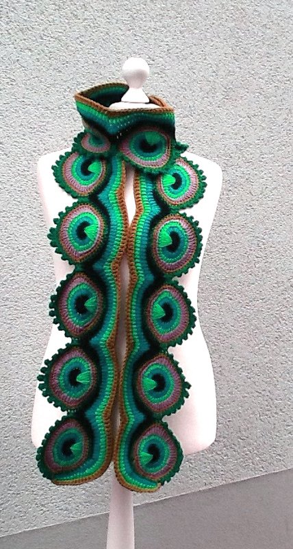 Gehäkelter grüner Schal mit kreisförmigen, gestaffelten Motiven auf einer Schaufensterpuppe