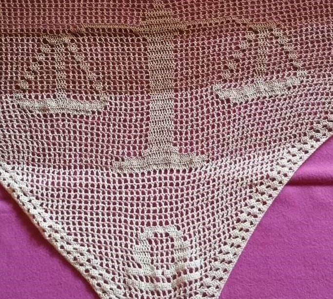 Dreieckiges beigefarbenes Häkeltuch mit Anker-Motiv auf violettem Untergrund.