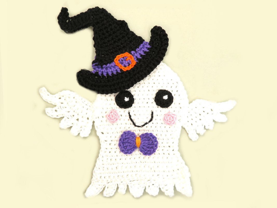 White crocheted ghost applique wearing a black witch hat with a purple band and orange buckle and a purple bowtie with an orange center.