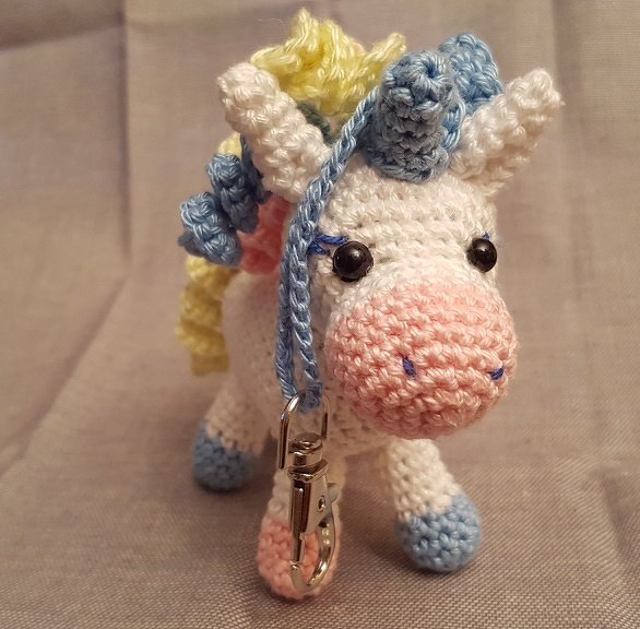 Gehäkelter Einhorn-Schlüsselanhänger, weiß mit pastellfarbener Mähne und Metallkarabiner