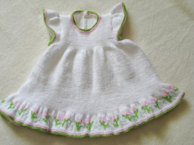 Weißes gestricktes Babykleid mit rosa-grüner Blumenbordüre am Saum