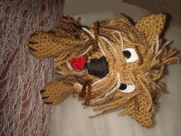Gehäkelter brauner Amigurumi-Hund mit fransigem Garnfell, schwarzer Nase und roter Zunge