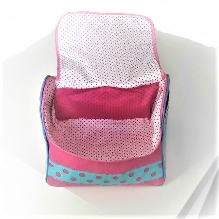 Offene pinke Kosmetiktasche mit türkisfarbenem Pünktchenband und gepunktetem Innenfutter