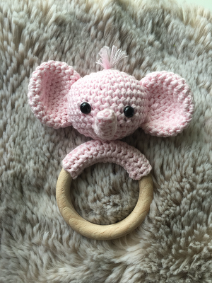 Rosa gehäkelter Elefanten-Beißring mit Holzring auf flauschigem Untergrund