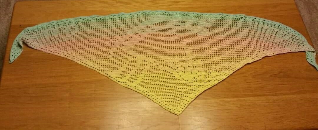 Gehäkeltes Dreieckstuch in Pastellverlauf mit Blütenmotiv auf Holzuntergrund