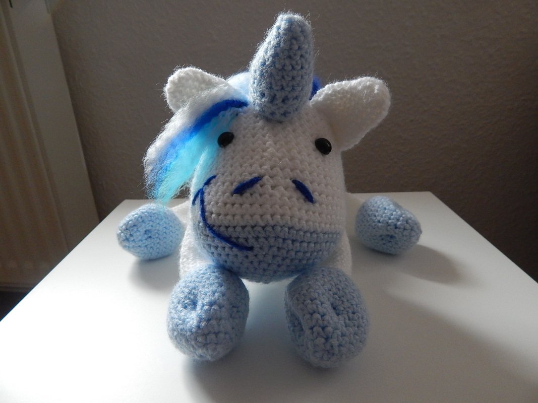Weißes gehäkeltes Einhorn-Amigurumi mit hellblauer Mähne und Horn