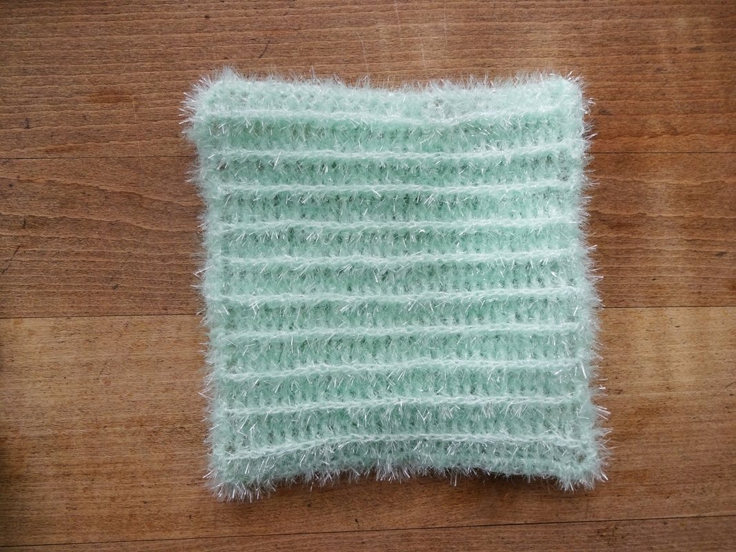 Quadratisches mintgrünes gehäkeltes Spültuch aus flauschigem Effektgarn auf Holz