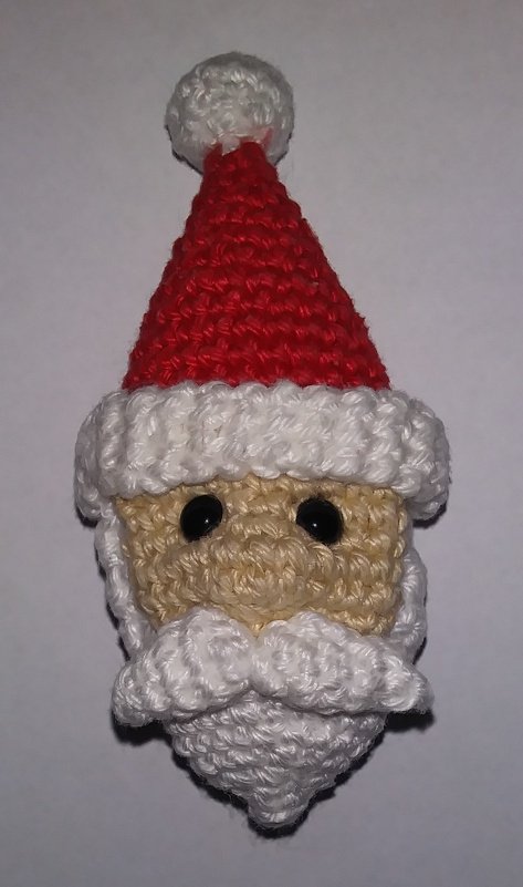 Kleiner gehäkelter Weihnachtsmannkopf mit roter Zipfelmütze und weißem Bart, Nahaufnahme