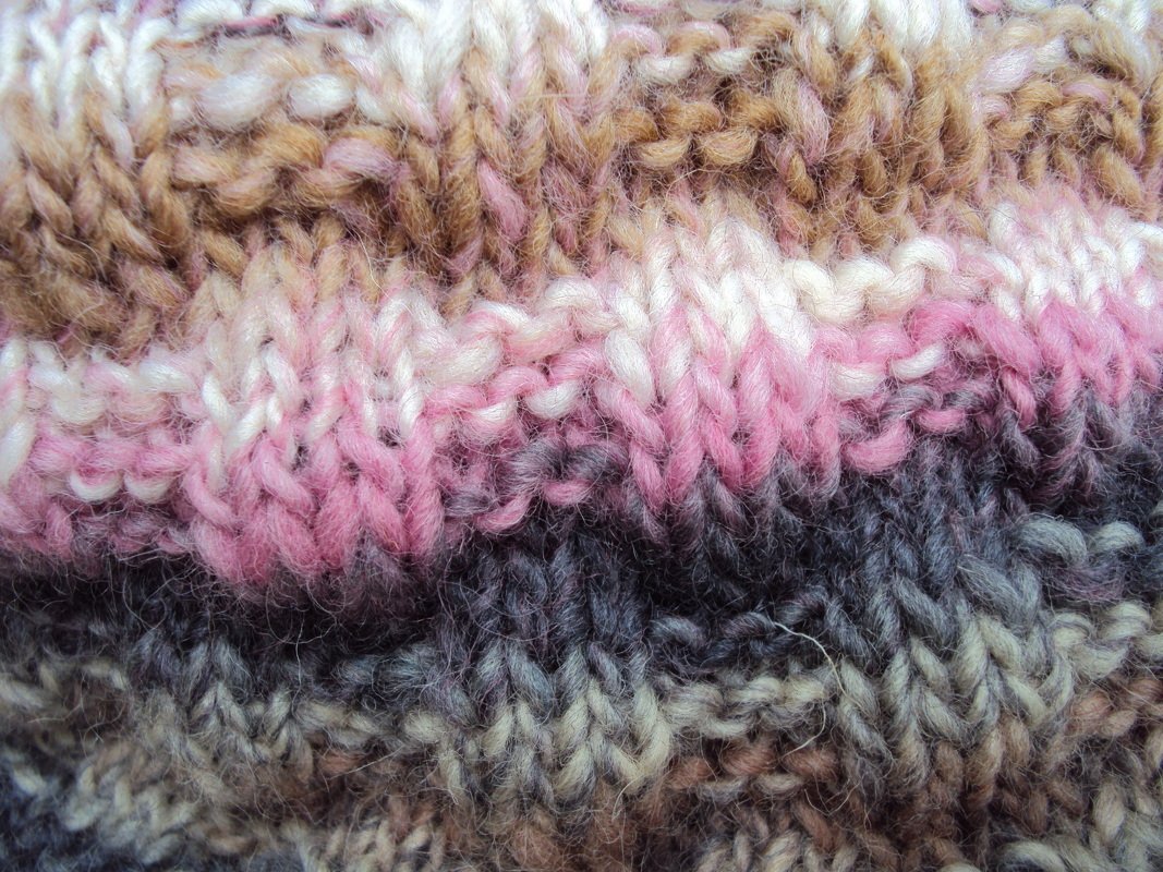 Nahaufnahme gestrickter Streifen in Rosa, Weiß, Braun und Grau