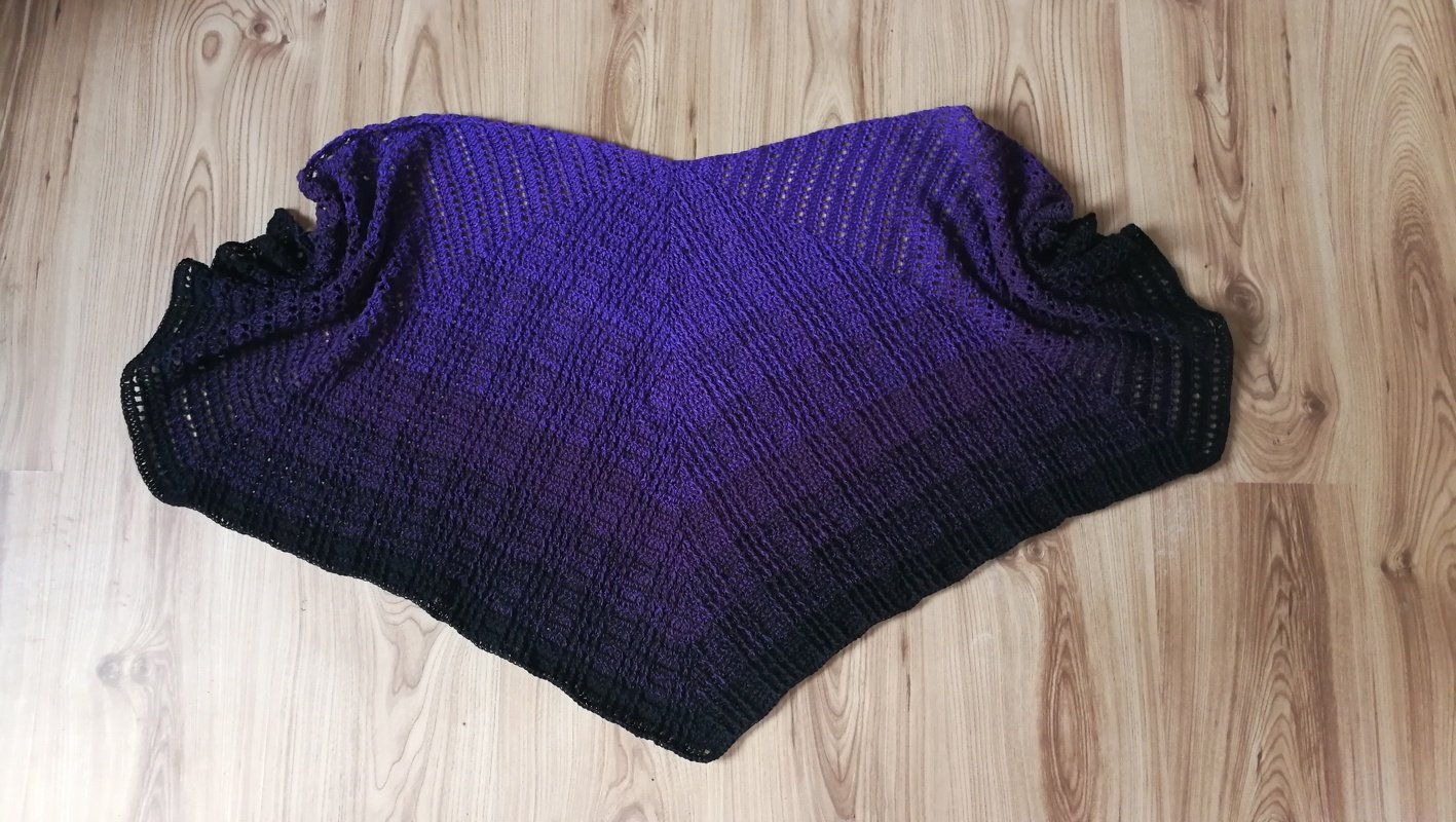 Symmetrisches gehäkeltes Dreieckstuch in Violett und Schwarz mit regelmäßigen Reihen auf Holzboden