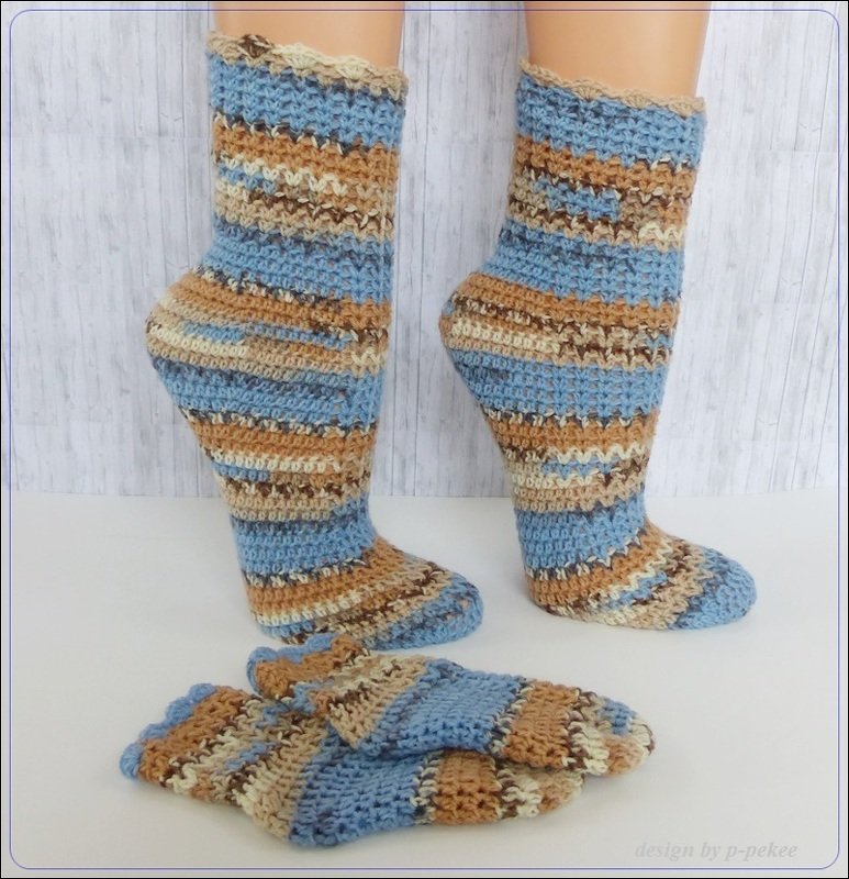 Gestreifte, wadenlange Socken aus gehäkeltem Garn auf Modellbeinen mit zusätzlichem Paar flach liegend