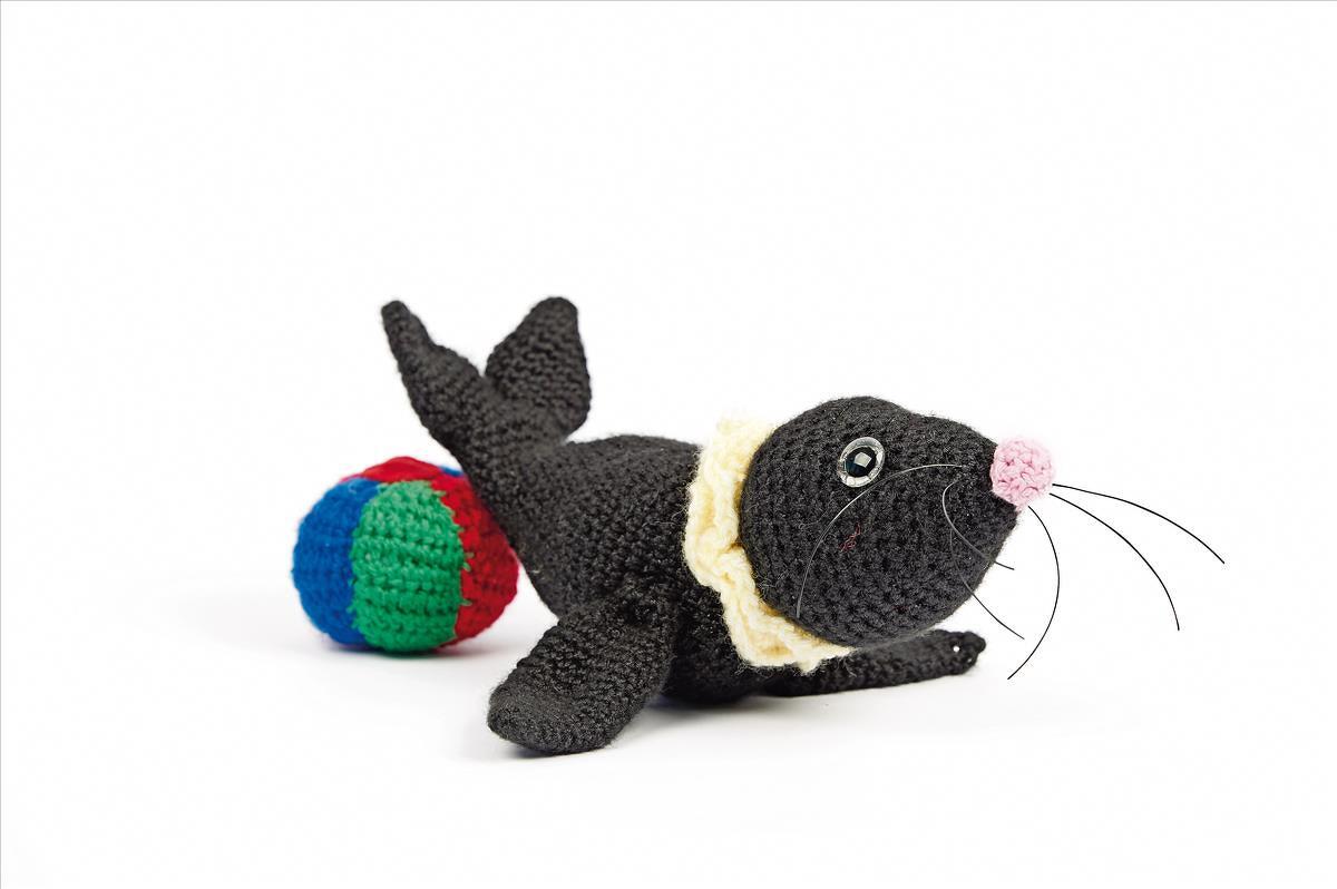Gehäkelte schwarze Robbe Amigurumi mit rosa Nase und buntem Ball