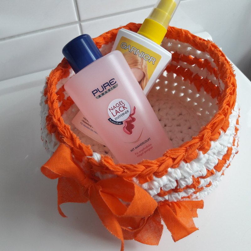 Praktisches gehäkeltes Utensilo in Orange und Weiß mit Schleife, gefüllt