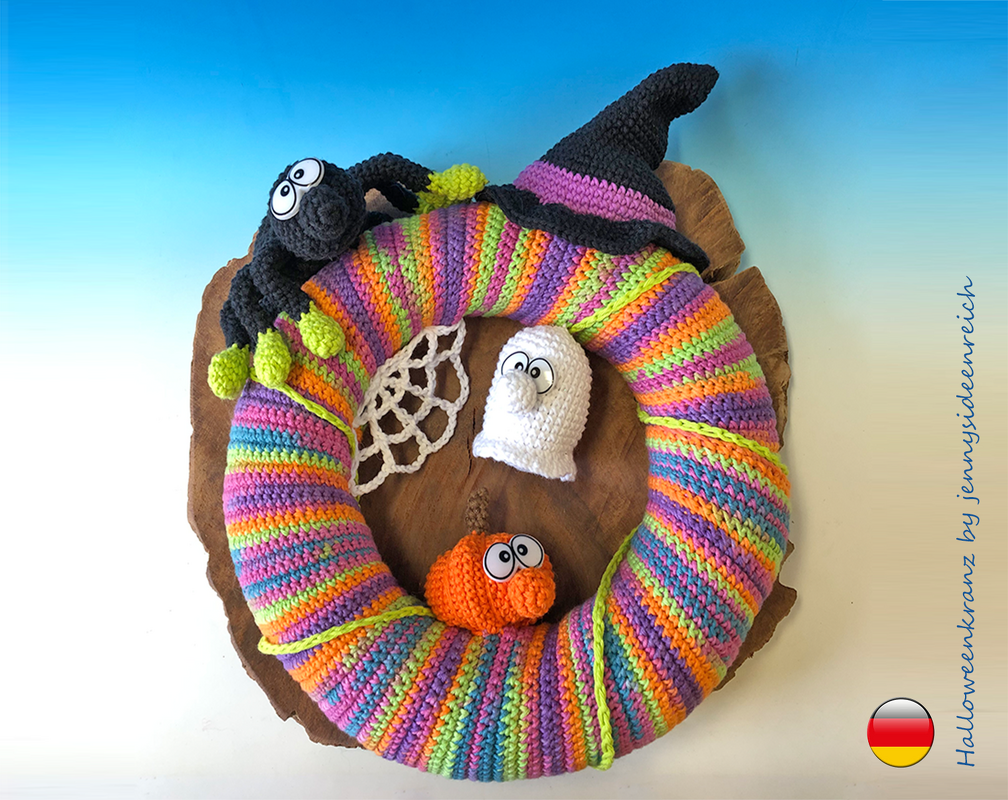 Farbenfroher, gehäkelter Halloween-Türkranz mit gestreiftem Muster, dekoriert mit Hexe, Spinne, weißem Geist und orangenem Kürbis auf Holzuntergrund