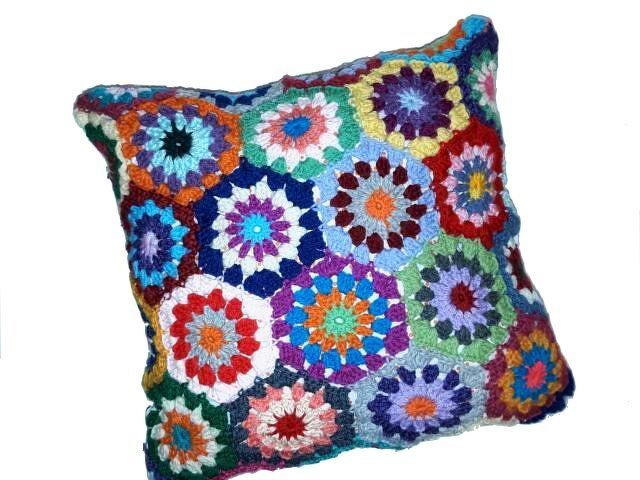Gehäkeltes Kissen aus sechseckigen Granny-Motiven in vielen leuchtenden Farben.