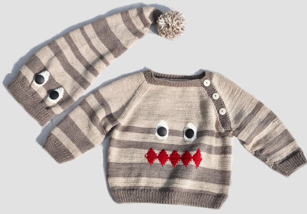 Gestreifter Baby-Strickpullover mit Knöpfen und passende Zipfelmütze mit Pompon, beides mit Monstergesicht-Applikation.