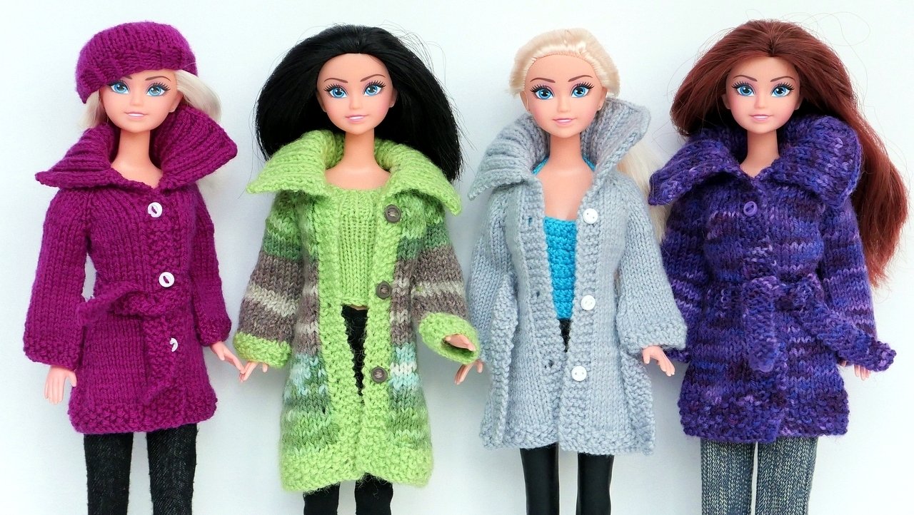 Vier Puppen mit unterschiedlichen gestrickten Mänteln in Lila, Grün, Grau und Violett
