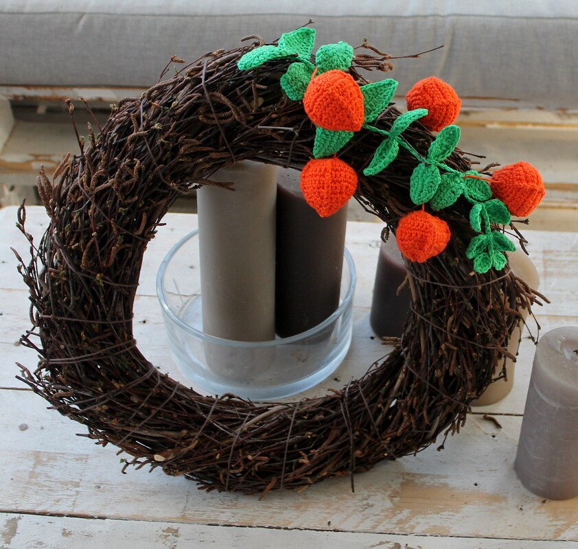 Kranz aus Zweigen mit gehäkelten orangefarbenen Beeren und grünen Blättern