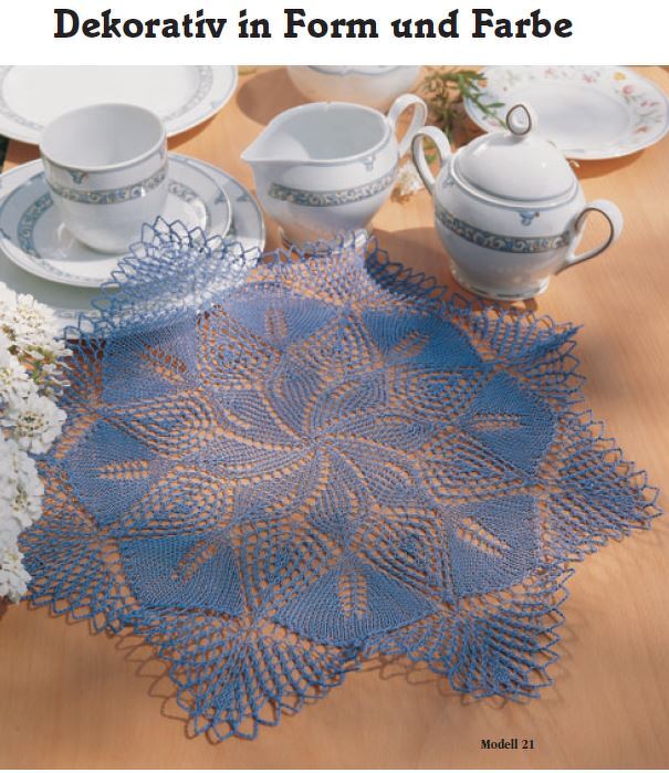 Blaues gehäkeltes Deckchen mit sternförmigem Muster auf Holztisch neben Porzellangeschirr