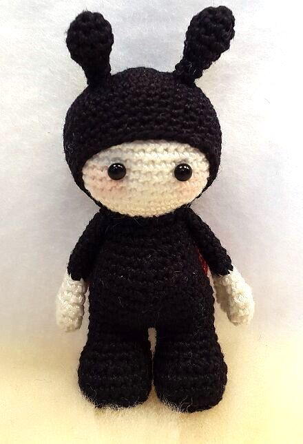 Gehäkelte Amigurumi-Puppe im schwarzen Ganzkörperkostüm mit cremefarbenem Gesicht, zwei Ohren und runden schwarzen Augen