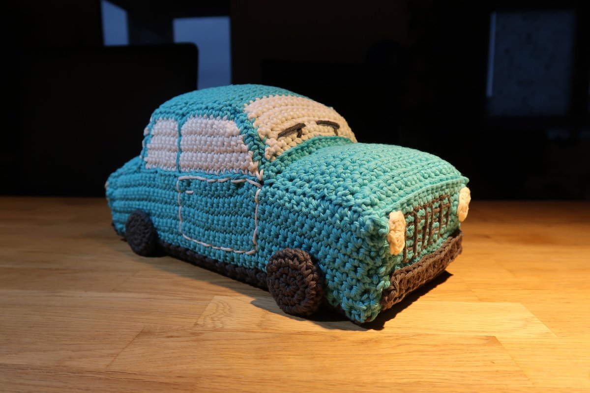 Gehäkeltes Amigurumi-Auto in Türkis und Weiß auf Holz