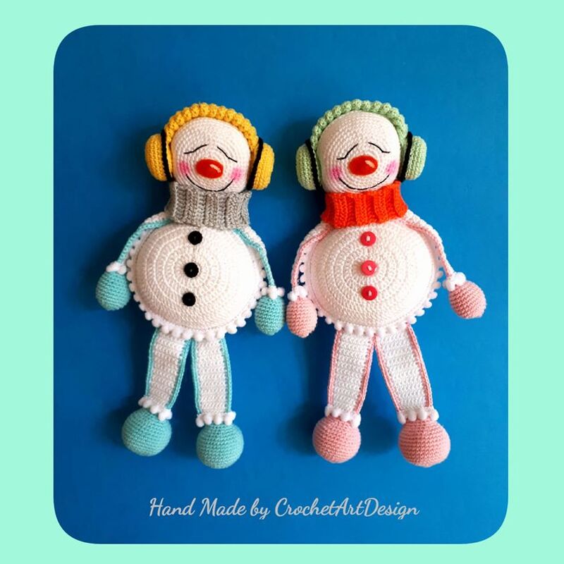 Zwei gehäkelte Schneemann-Figuren mit Ohrenschützern und Schals auf blauem Untergrund