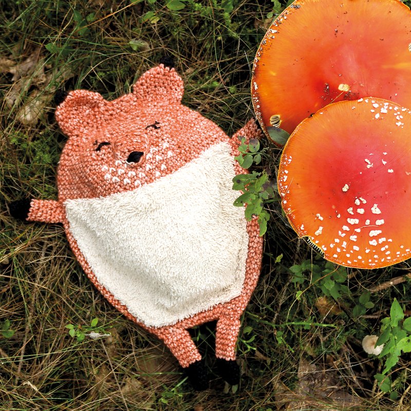 gehäkeltes orange‑weißes Fuchs‑Schmusetuch mit gestickten Augen auf Gras