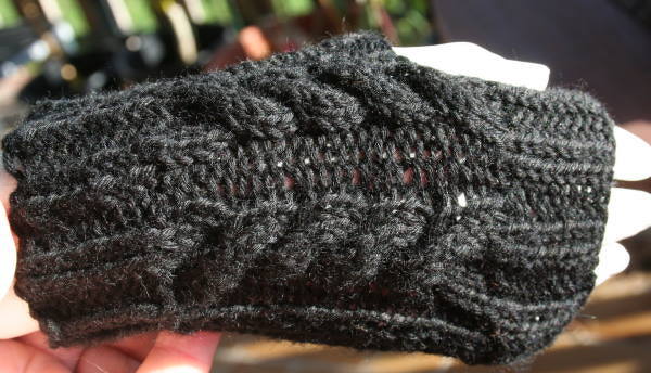 Schwarze gestrickte fingerlose Armstulpe mit Zopfmuster und Rippbündchen