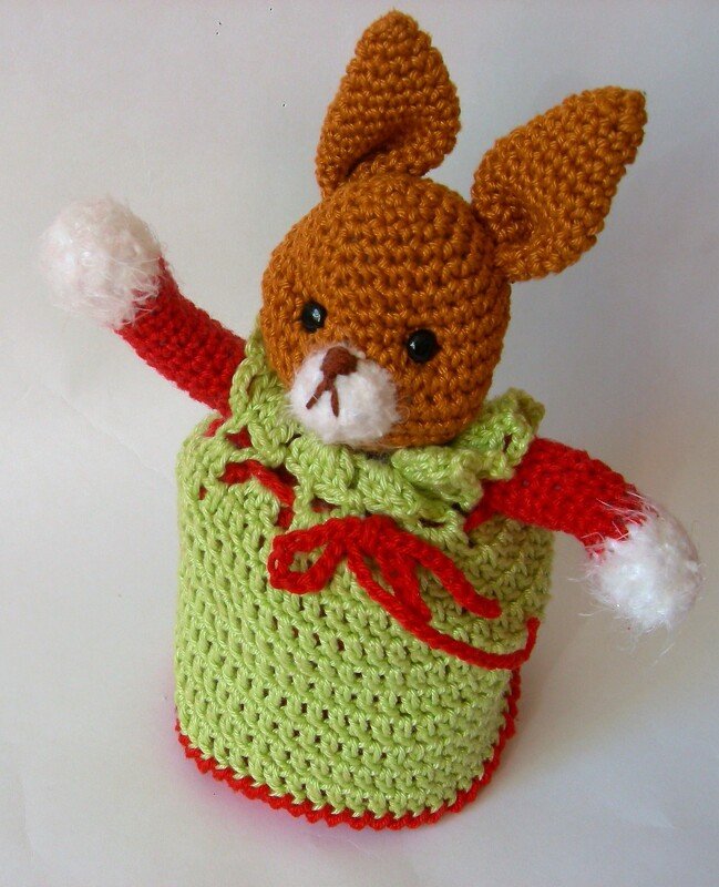 Gehäkelter Amigurumi-Hase brauner Kopf grünes Gewand rote Ärmel weiße Bündchen