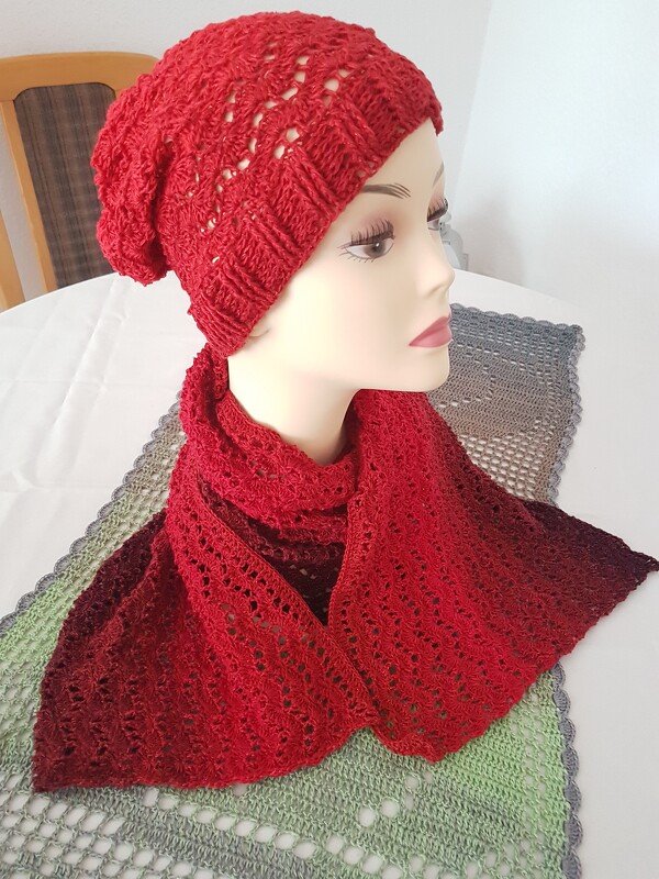 Rotes gehäkeltes Damen-Set mit Mütze und Schal auf Schaufensterpuppe