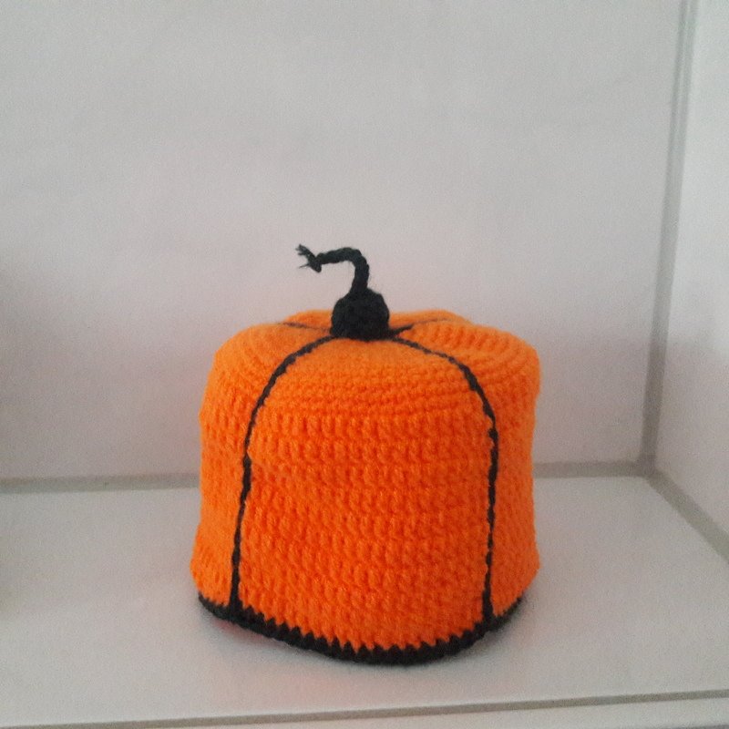 Gehäkelter orangefarbener Kürbis mit schwarzem Stiel als Dekoration