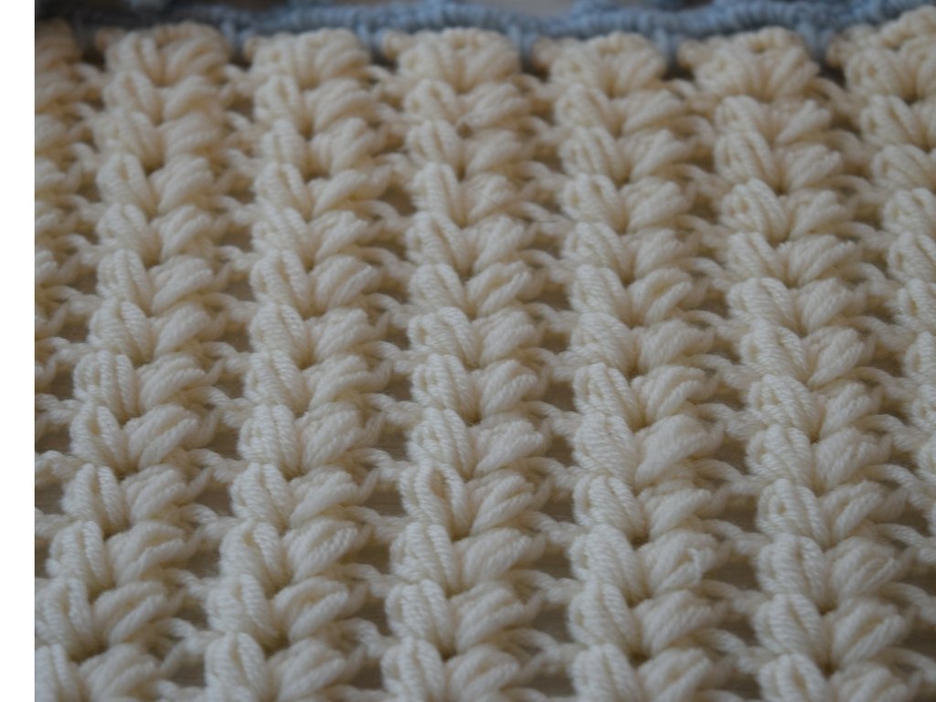 Gehäkeltes Textil in Creme mit Noppenmuster und blauem Rand