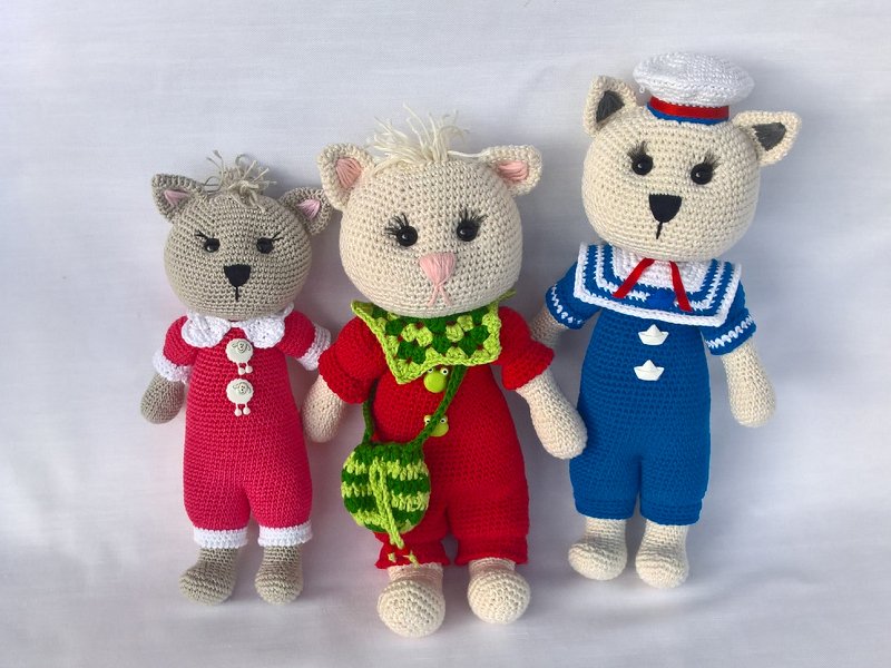 Drei gehäkelte Amigurumi-Tierfiguren in pinkem, rotem und blauem Outfit, rechts im Matrosenanzug mit Mütze