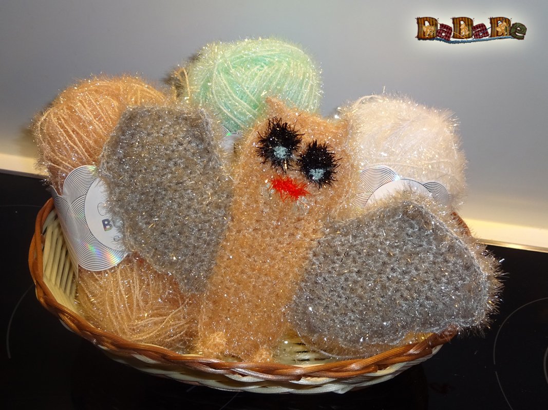 Kuschelige gehäkelte Eule mit großen, dunklen Augen und oranger Schnabelimitierung im Korb