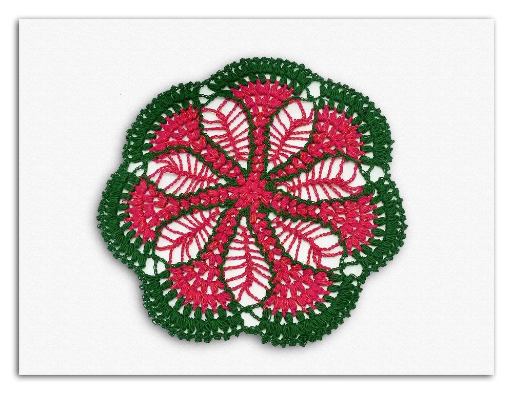 Rundes Häkelmotiv in Grün und Rosa mit sternförmigen Blütenblättern und offenem Spitzenmuster
