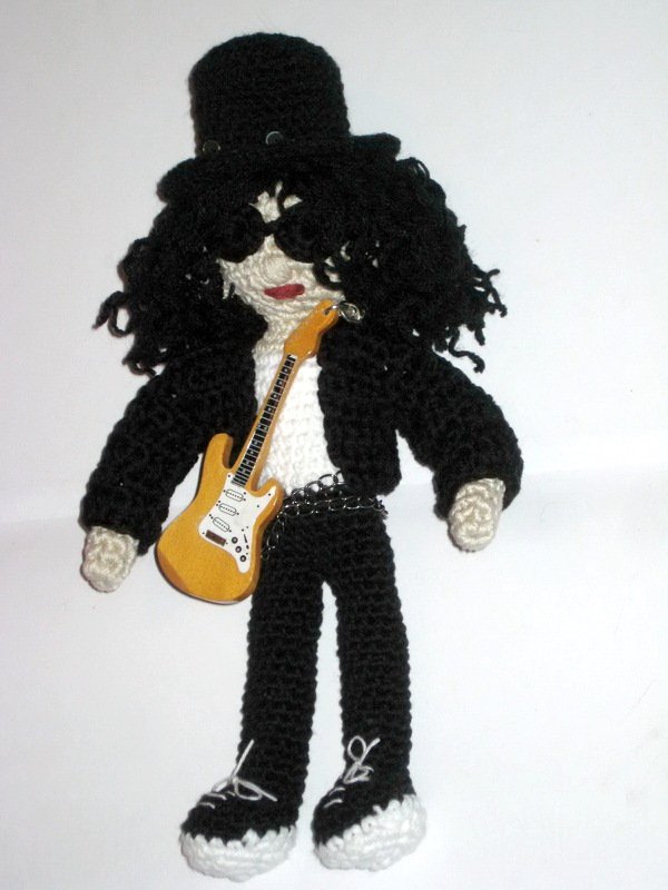 Hand-crocheted amigurumi doll dressed as a rock star with a black top hat, curly hair, sunglasses, black outfit, and yellow electric-style guitar.
