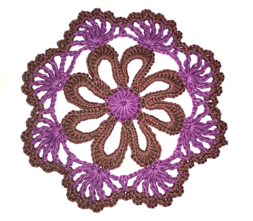 Rundes gehäkeltes Deckchen mit braunen Blütenblättern und lila Spitzenrand