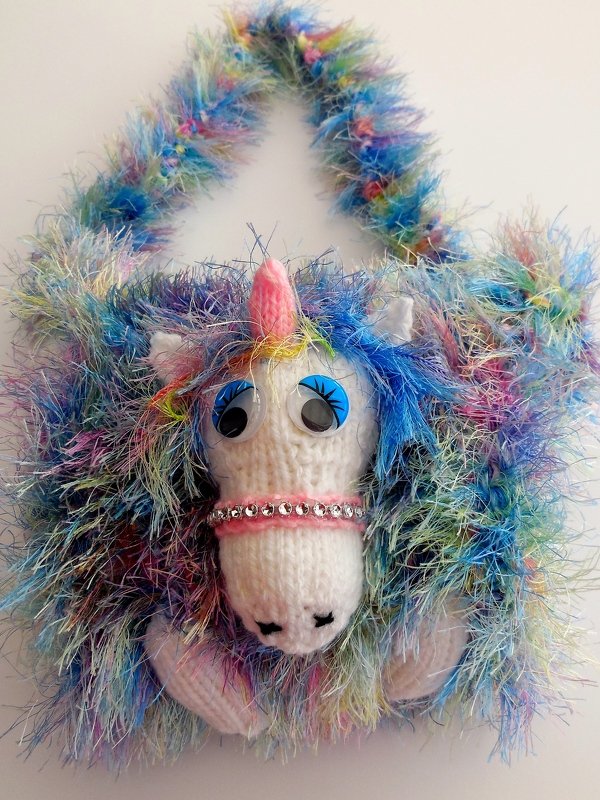 Gestrickte Einhorn‑Handtasche in Regenbogenfarben mit Wackelaugen, rosa Horn und Strassband