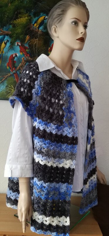 Mannequin mit gehäkelter, ärmelloser Weste in Blau‑Grau‑Weiß mit Muschelmuster über weißer Bluse