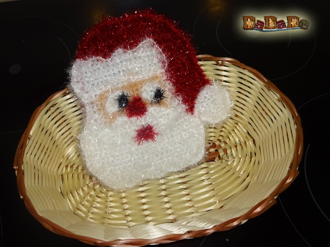 Gehäkelter Weihnachtsmann-Kopf mit roter Glitzermütze in hellem Flechtkorb