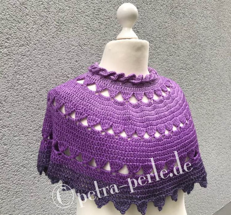 Violetter gehäkelter kurzer Poncho mit Lochreihen und Zackenrand auf Schaufensterpuppe