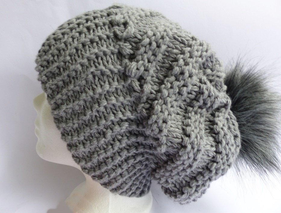 Graue Strickmütze mit strukturiertem Muster und großem grauen Bommel