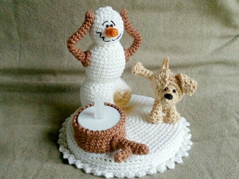 Gehäkelter weißer Schneemann mit braunen Armen neben kleinem beigen Hund auf runder weißer Häkelbasis mit braunem LED-Teelichthalter
