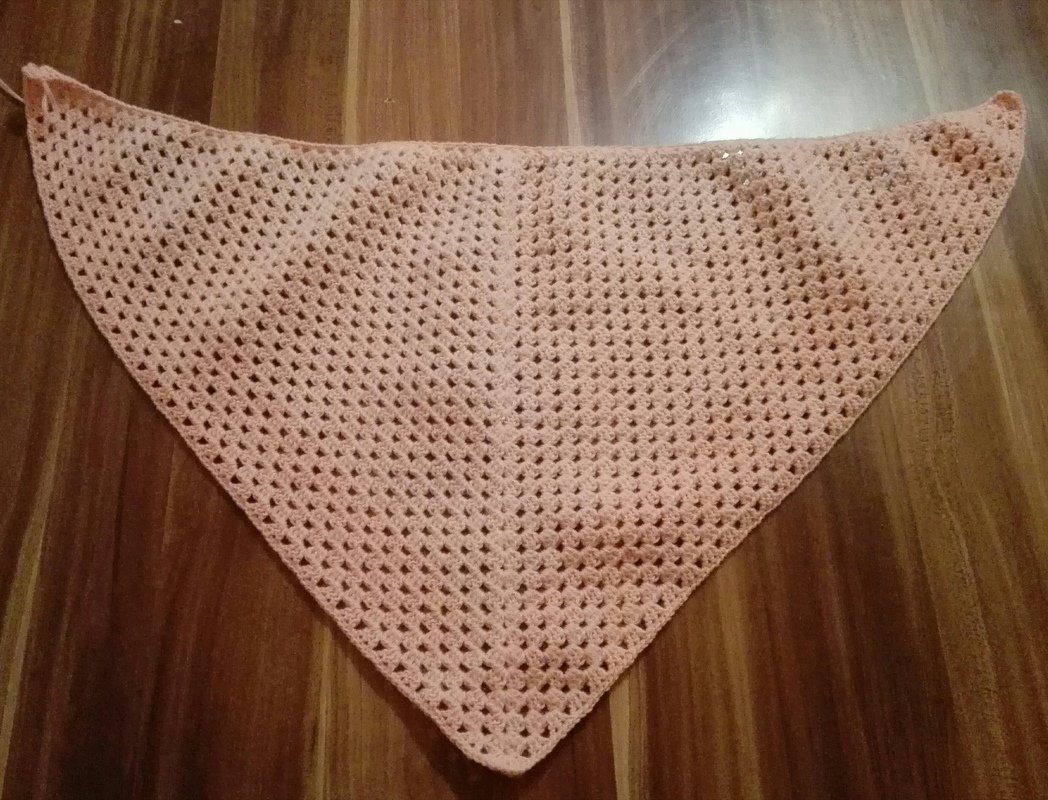 Gehäkeltes Dreieckstuch in Rosé mit Granny-Muster auf Holzboden