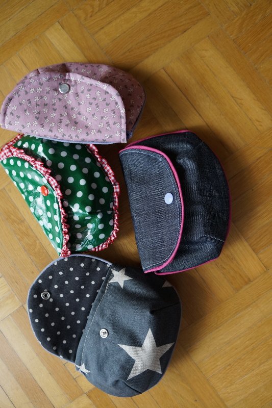 Vier kleine Kosmetiktaschen mit Sternen, Punkten, Jeansoptik und floralem Stoff auf Parkett