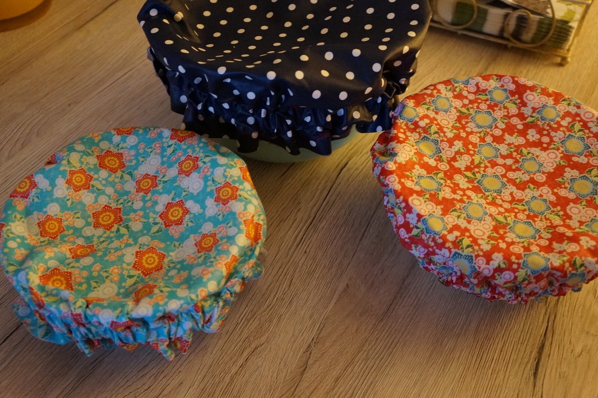 Drei genähte Stoff-Schüsselabdeckungen mit Gummizug: dunkelblau mit weißen Punkten, türkis-blumig und rot-blumig