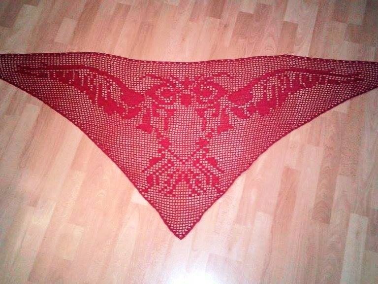 Rotes Dreieckstuch, gehäkelt mit einem durchbrochenen Muster, auf einem Holzboden