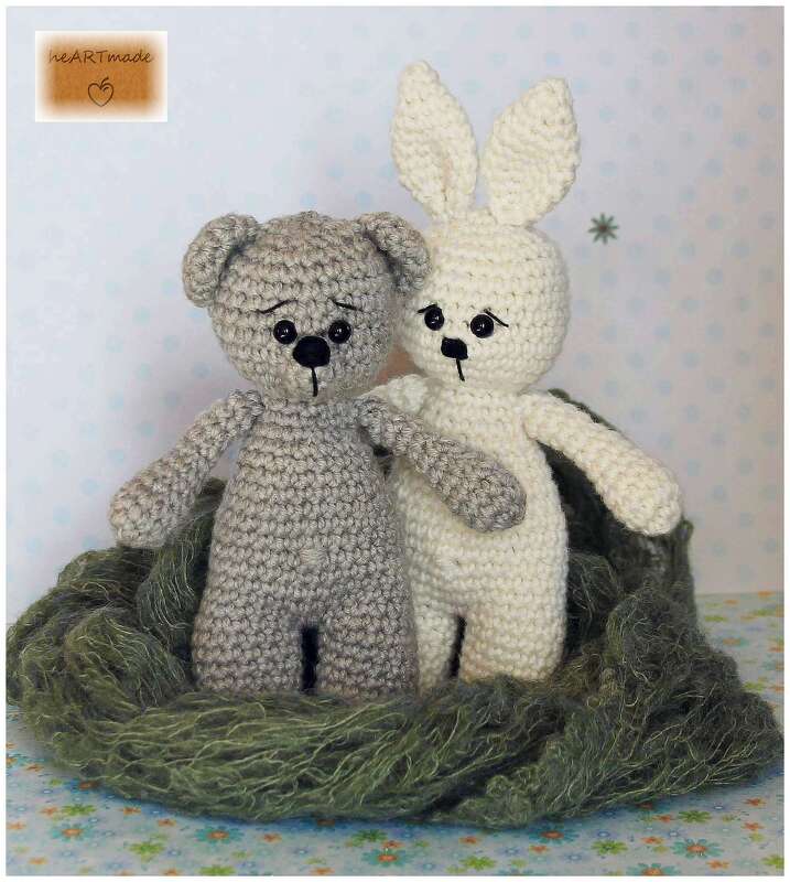 Gehäkelter grauer Teddybär und weißer Hase in grünem Wollnest