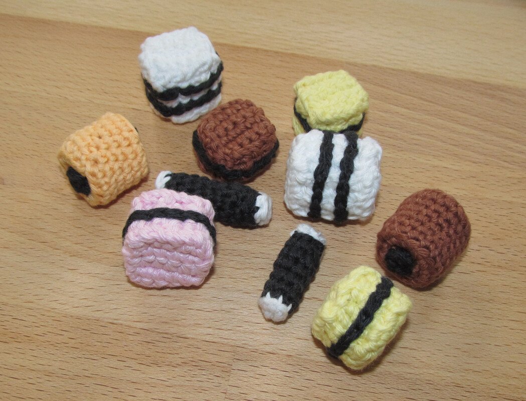 Mehrere gehäkelte Bonbons in Pastell- und Brauntönen auf Holzuntergrund